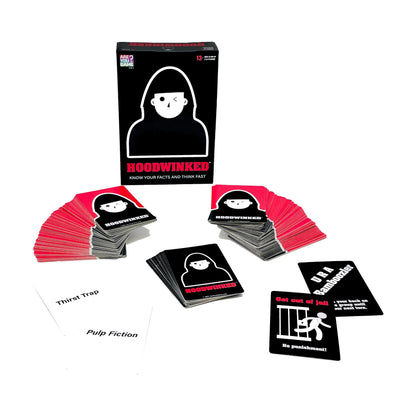 Hoodwinked card game box and contents displayed, showing black game box with white hooded figure icon, stacks of pink and black cards fanned out, and sample car