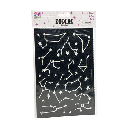 Glow-in-the-dark zodiac adhesive shapes set featuring white constellation outlines and stars on black background, packaged in labeled header card