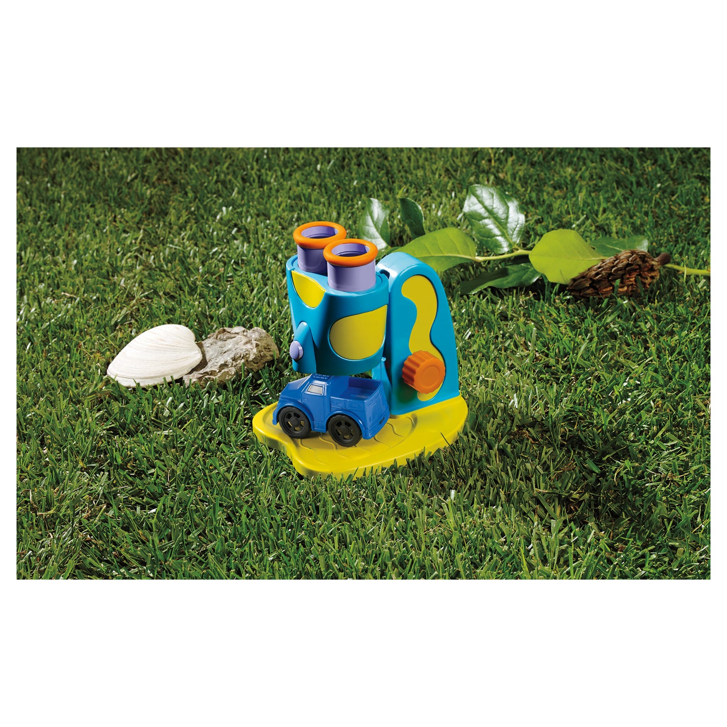 GeoSafari Jr. STEM Microscope with blue and yellow body, orange eyepieces, and LED light on grass