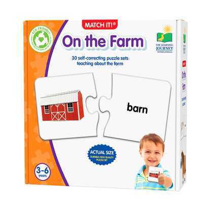 Match It! On the Farm puzzle game box showing a red barn puzzle piece matching with the word 'barn', modeled by a child aged 3-6 years