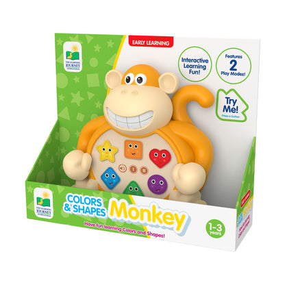 Orange and cream interactive monkey toy with smiling face, colorful shape buttons on belly, and large rounded ears, in packaging labeled Colors & Shapes Monkey