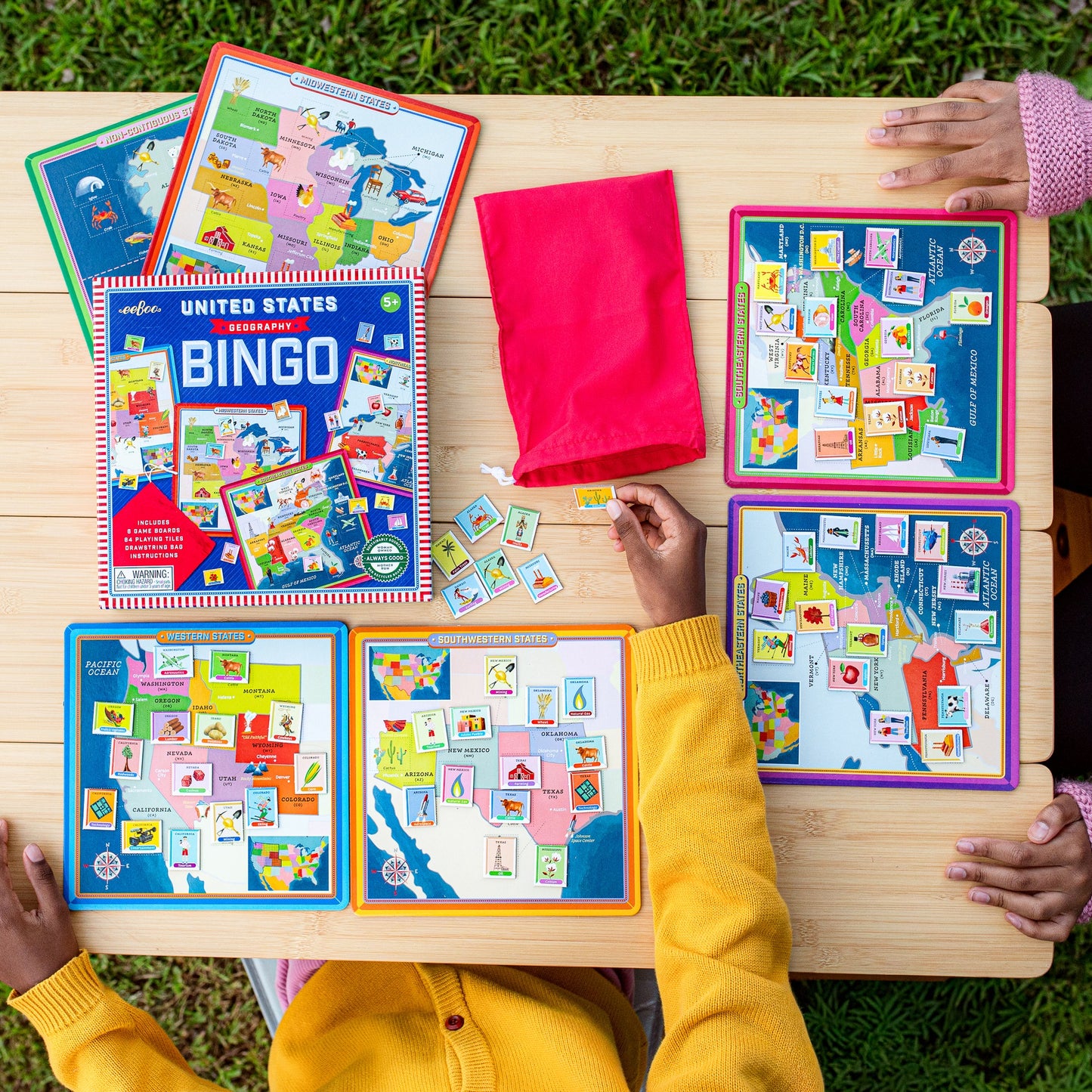 United States Geography Bingo game with colorful game boards, cards, and tiles on wooden table