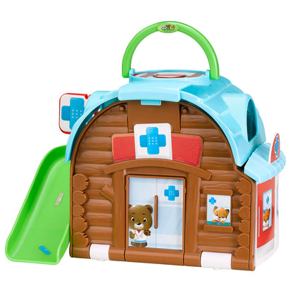 Brown log cabin-shaped playset with light blue roof and green handle, featuring medical cross symbols, opening doors with bear figurine visible, and green slide