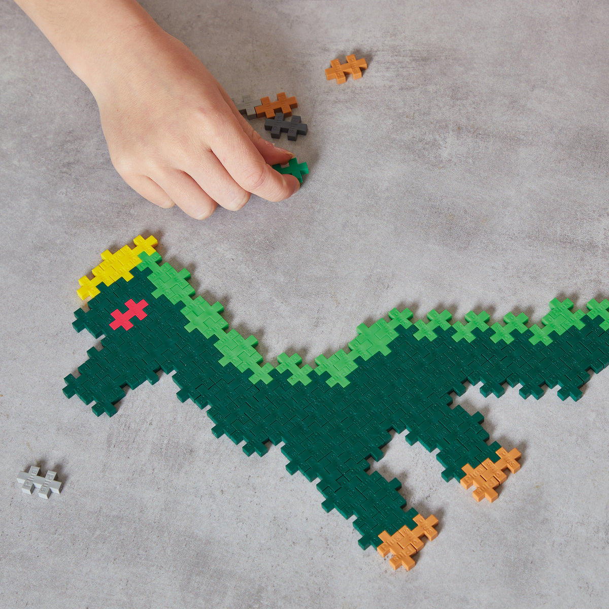 Plus-Plus Dinosaurs 400-piece set with green T-Rex, yellow details, and loose colorful blocks