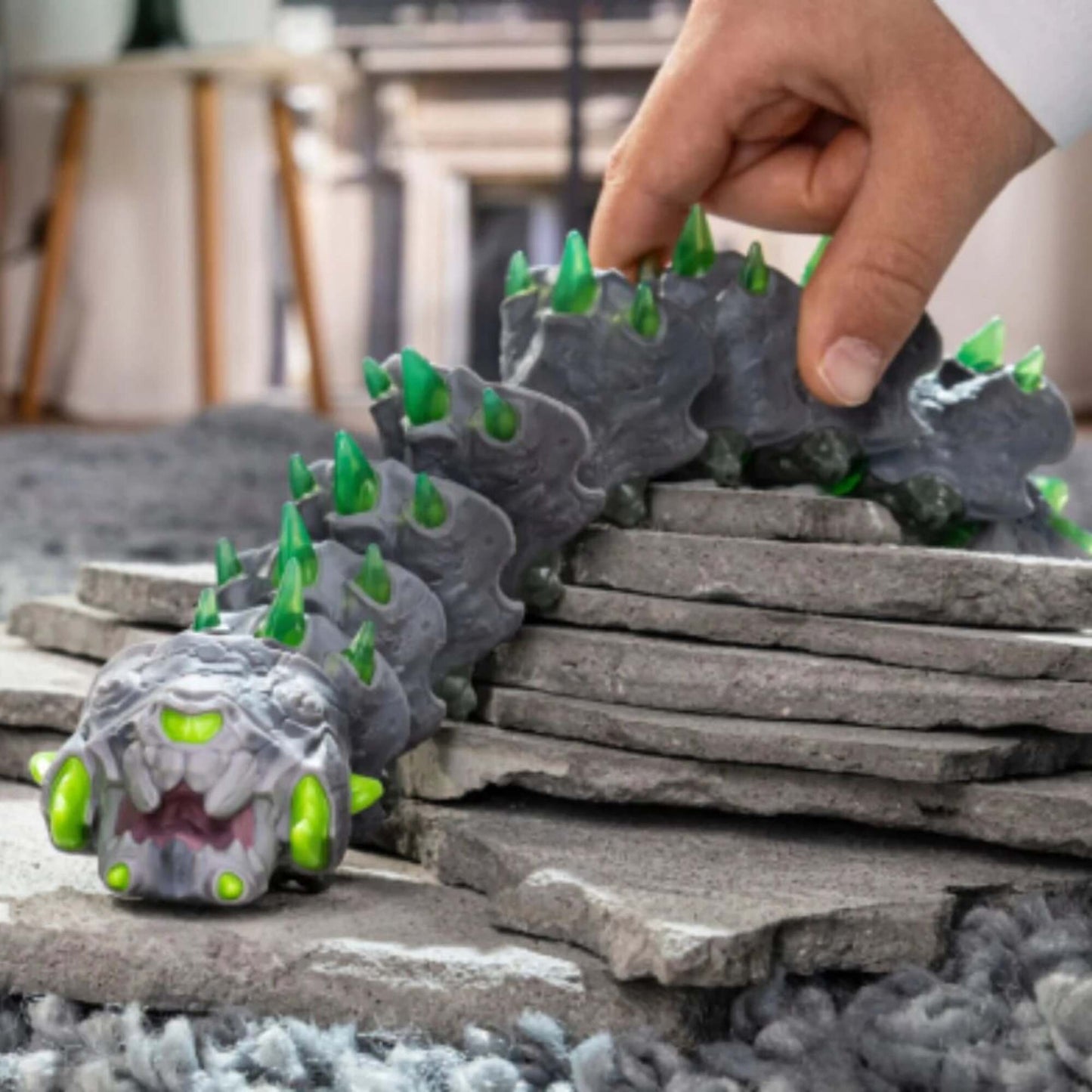Eldrador Creatures Stone Worm toy with gray body, green spikes and glowing eyes